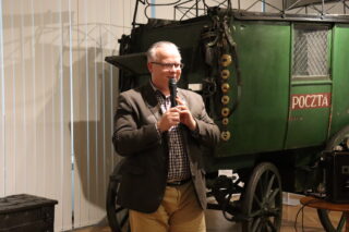 Prelegent przemawia przy dużym zielonym furgonie pcoztowym