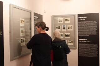 Para zwiedzających ogląda gablotę z aparatami telefonicznymi i opisami.