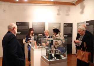 Zwiedzający oglądają centralnie ustawioną gablotę z urządzeniami łączności.