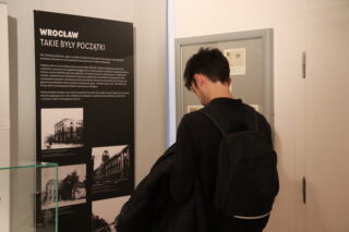 wiedzający oglądają eksponaty telefoniczne w szklanej gablocie.