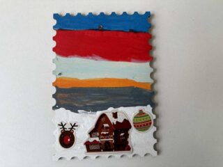 Kolorowa ozdoba choinkowa w kształcie znaczka pocztowego.