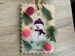 Drewniana ozdoba choinkowa w kształcie znaczka pocztowego.