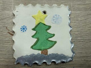 Ozdoba choinkowa w kształcie znaczka pocztowego z wizerunkiem choinki.