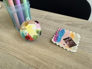 Kolorowa bombka i ozdoba choinkowa przypominająca znaczek pocztowy.